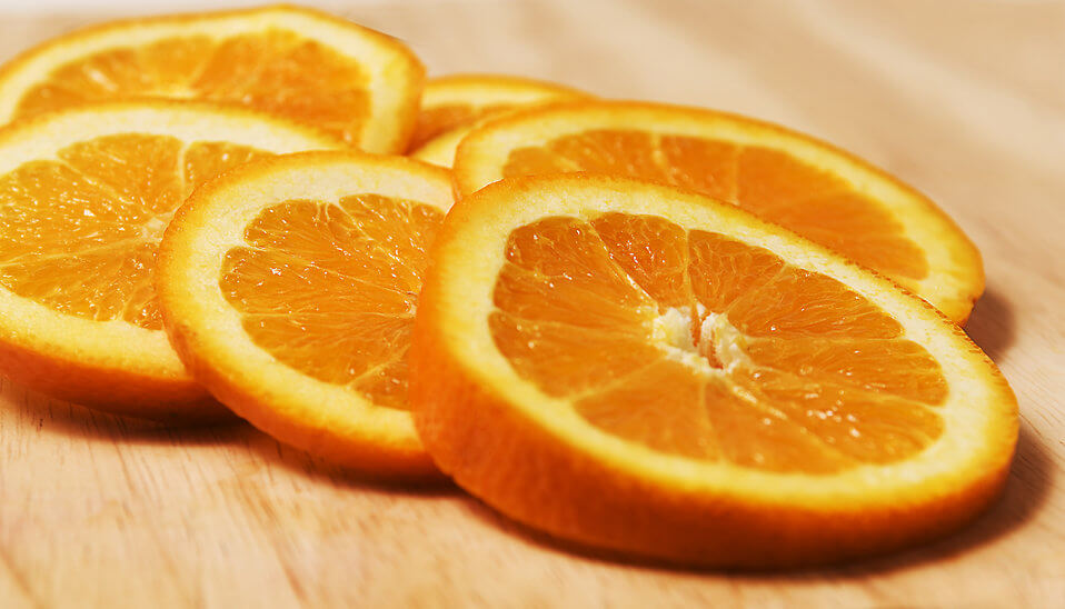 Seven orange slices displayed on a wooden cutting board.