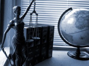 Lady Justice statue on a desk with law books and globe to represent ADA and Section 508