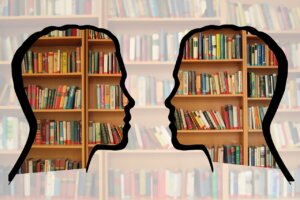 a silhouette of two heads facing each other against a backdrop of a library shelf of books